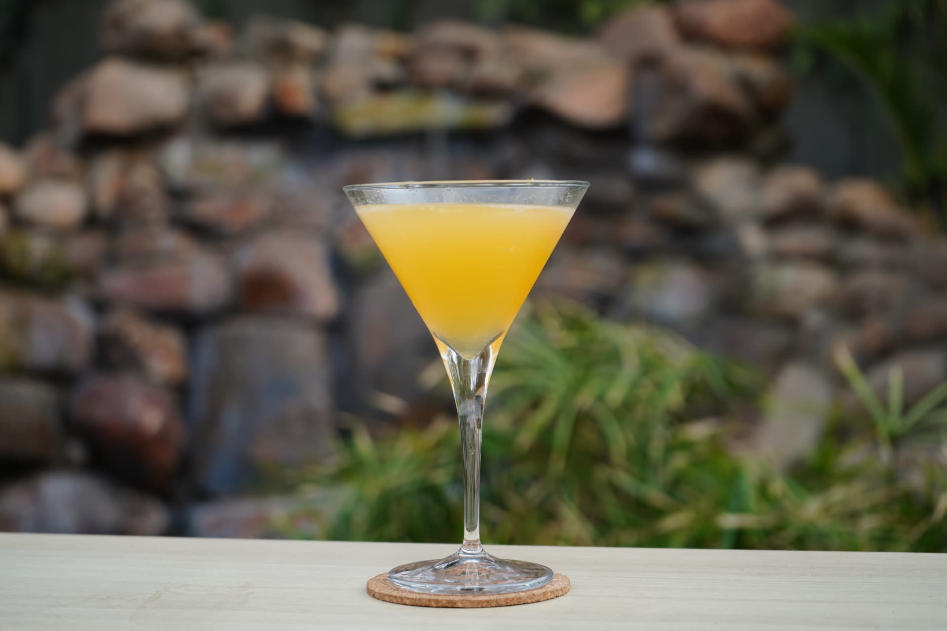 Orange martini against the garden waterfall