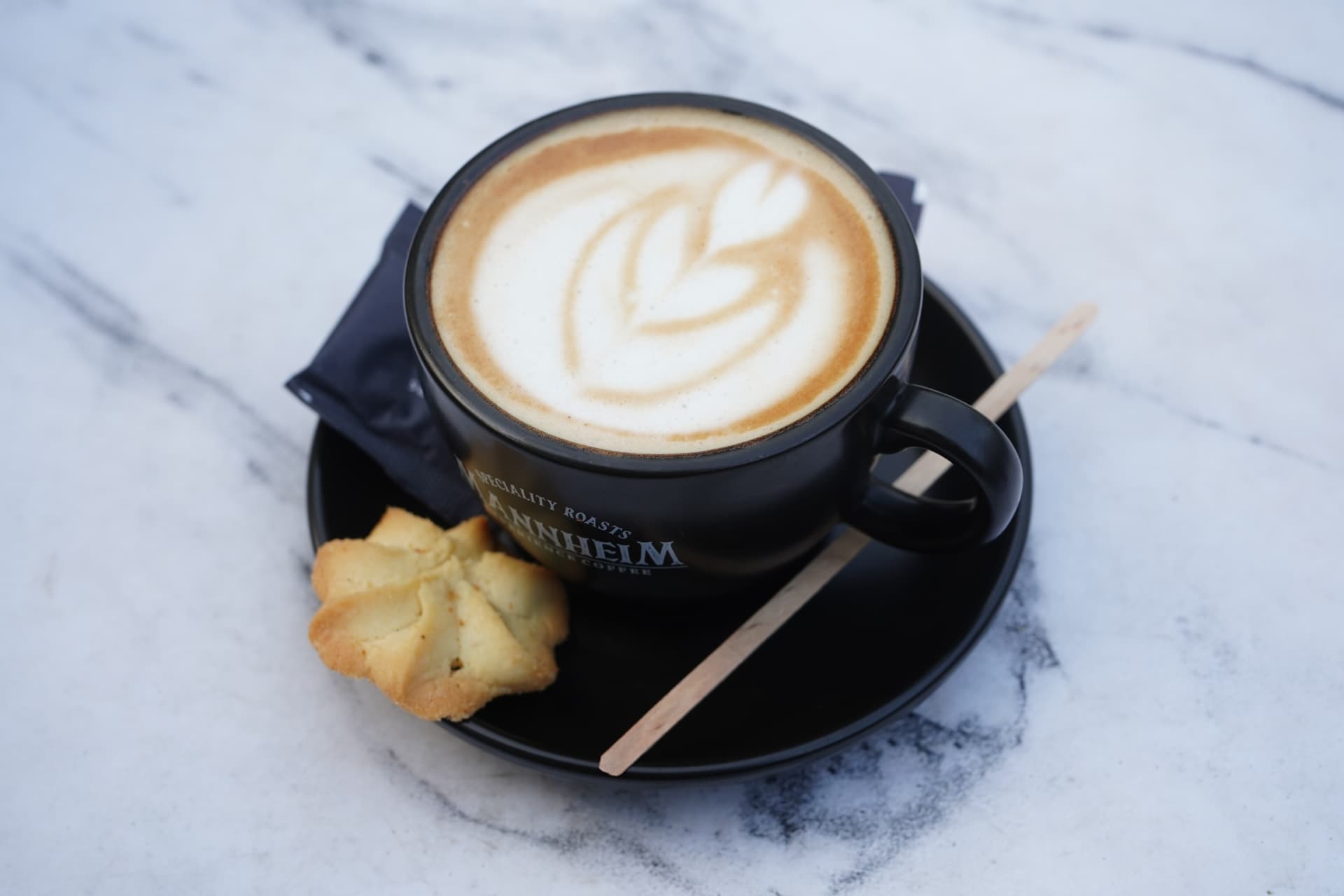 Latte with tulip latte art beside a butter cookie