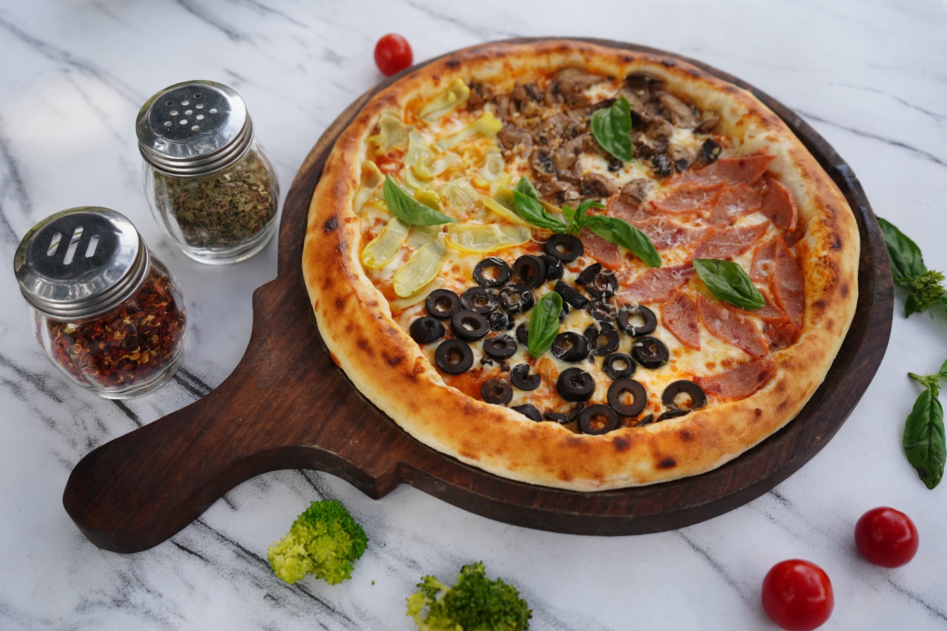Four-topping pizza with olives, mushrooms, ham and artichoke